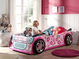 kleines Rennwagenbett für Mädchen in rosa im Kinderspielzimmer mit Mädchen sitzend auf dem Bett